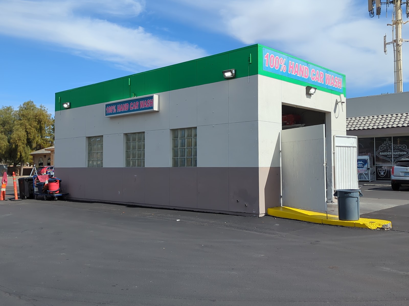 Exterior of the 100% Hand Car Wash building with green and pink signage