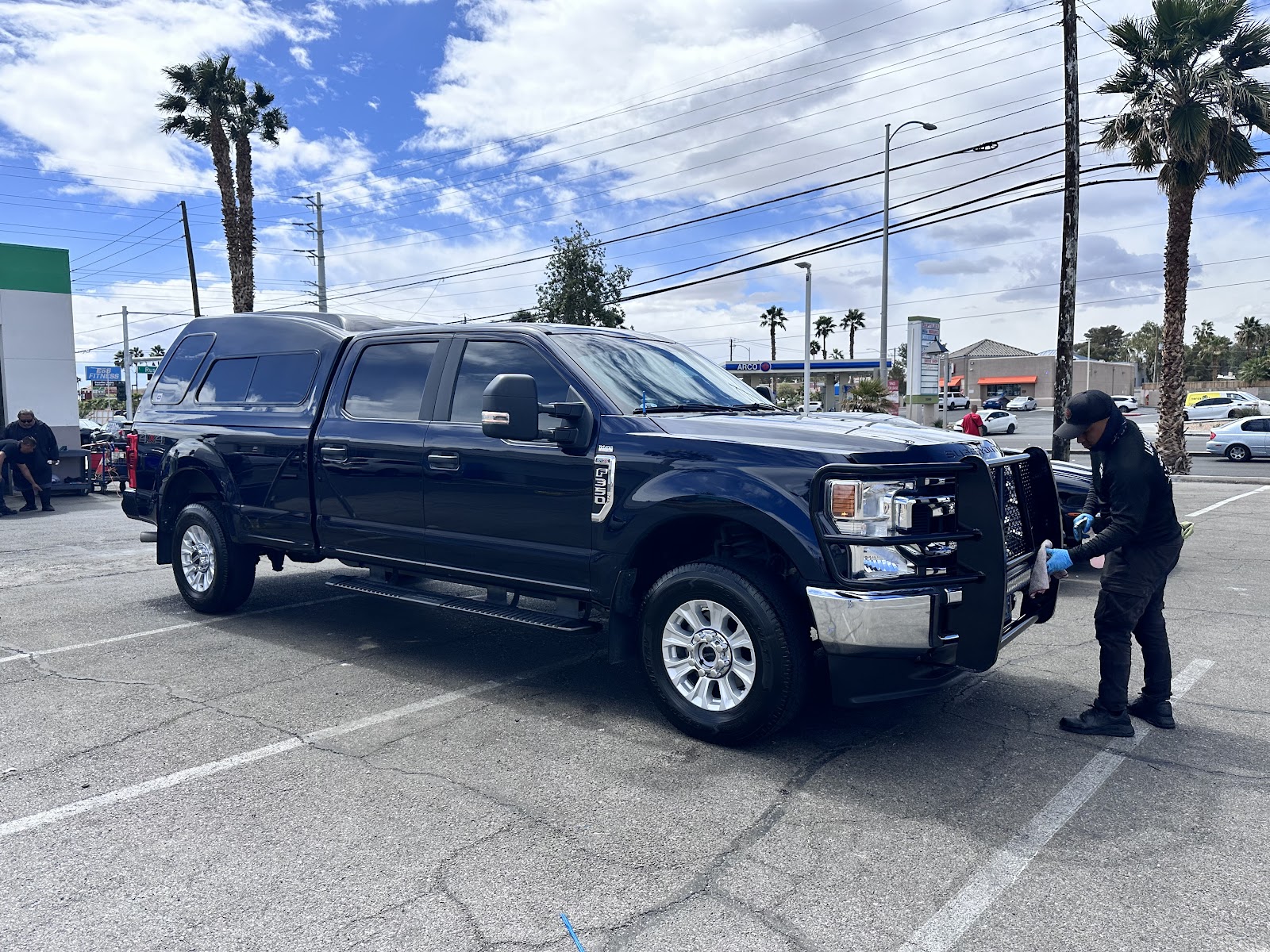Detailer wiping down a clean blue Ford F-350 truck at the car wash